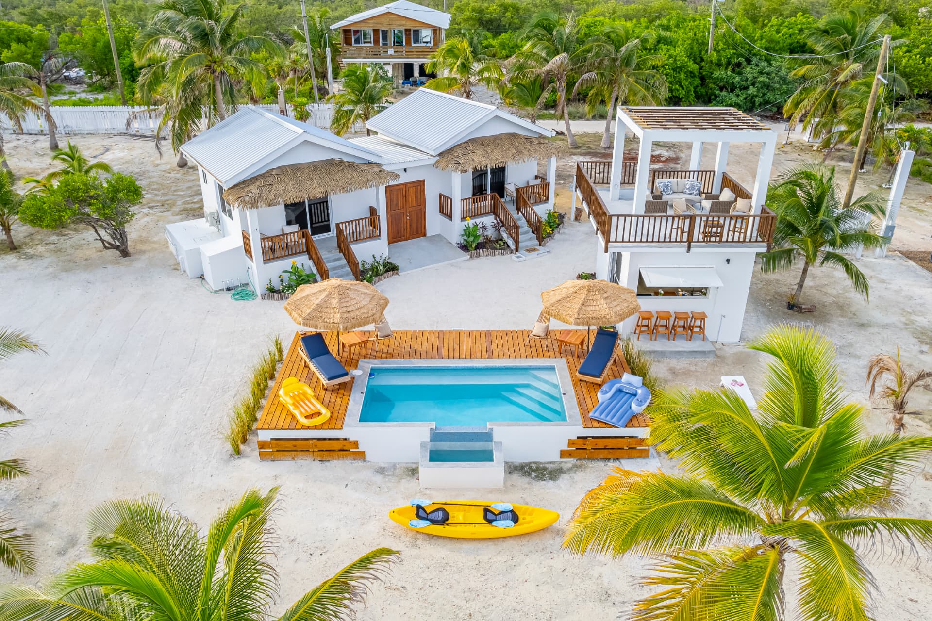 Aerial view of Belize Seaside Casitas: two white casitas, a pool deck with loungers, and the Seaside Lounge with its rooftop terrace